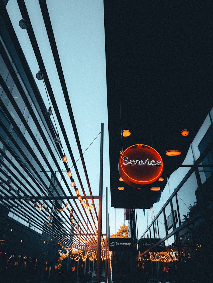 Contemporary building exterior featuring a striking neon sign and reflective glass facade at twilight.