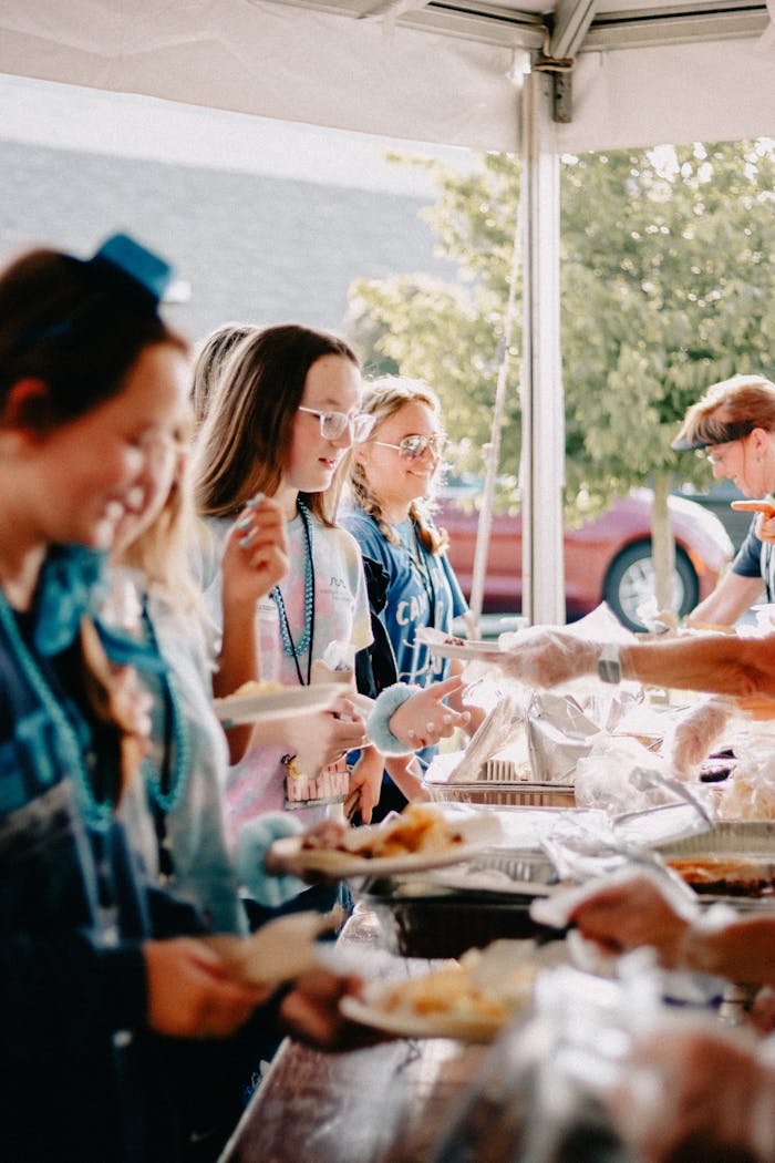 Joyful outdoor church gathering in Clemson with people sharing a meal under a tent.