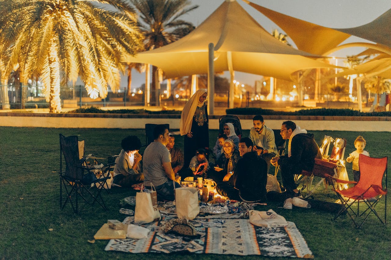 A group of people enjoying a cozy outdoor gathering under palm trees in Abu Dhabi at night.