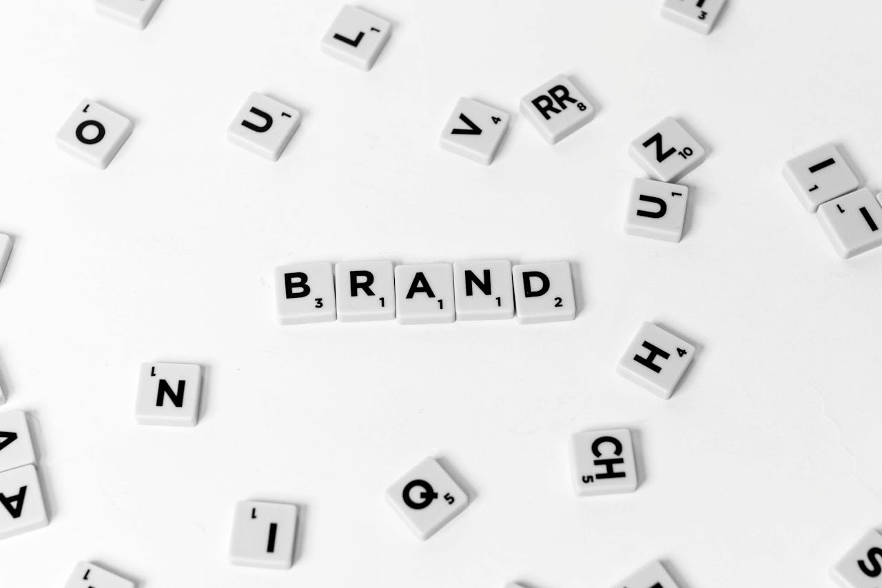 A flat lay of scattered letter tiles forming the word 'BRAND' on a white background.